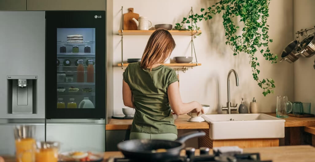 Vrouw kookt naast lg amerikaanse koelkast door-in-door